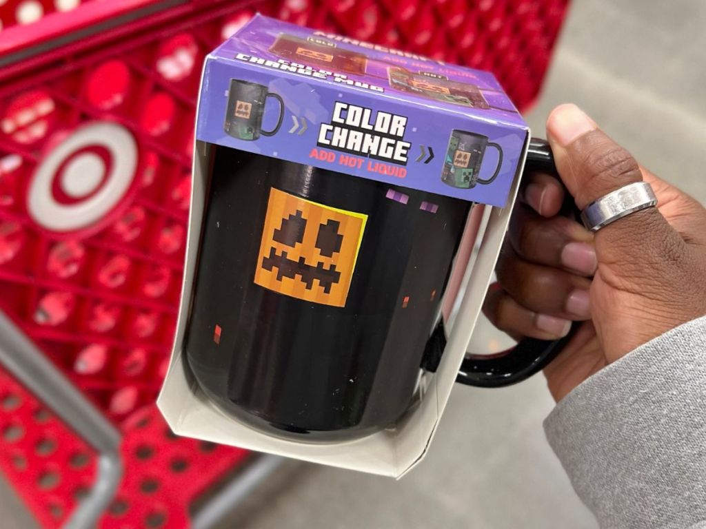 A hand holding Zak Minecraft Color Changing Mug in front of a Target cart