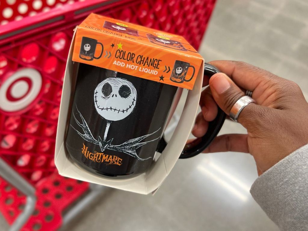 A hand holding Zak Nightmare Before Christmas Color Changing Mug in front of a Target cart