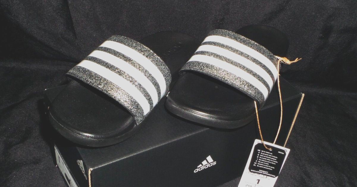 a pair of black and silver sparkly adidas kids slides