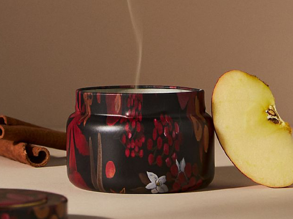 anthropologie capri blue spiced cider candle displayed with a cinnamon stick and an apple