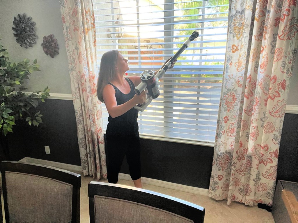 woman using a belife vacuum to clean her blinds