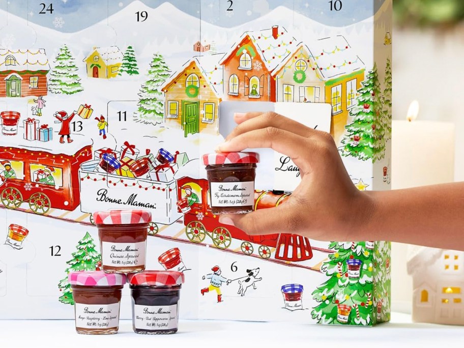 hand holding jam in front of bonne maman advent calendar