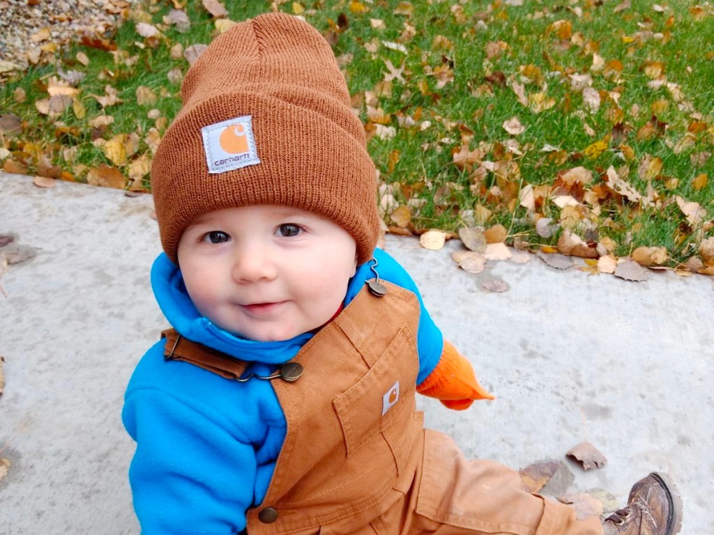 toddler wearing brown carthartt beanie while sitting on sidewalk
