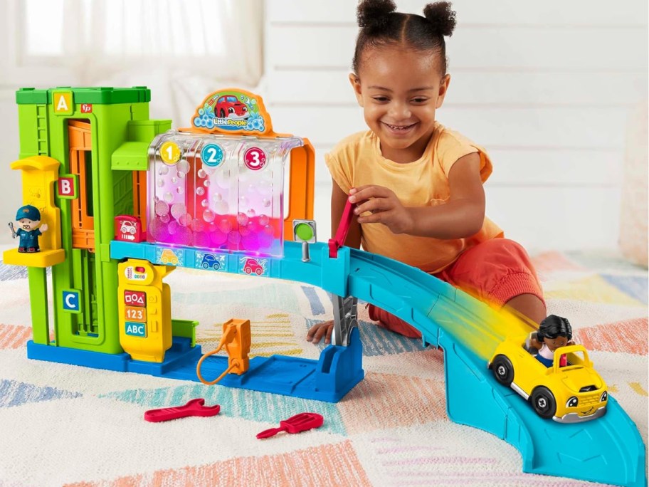 child playing with Fisher-Price Little People Light-Up Learning Garage Toddler Playset