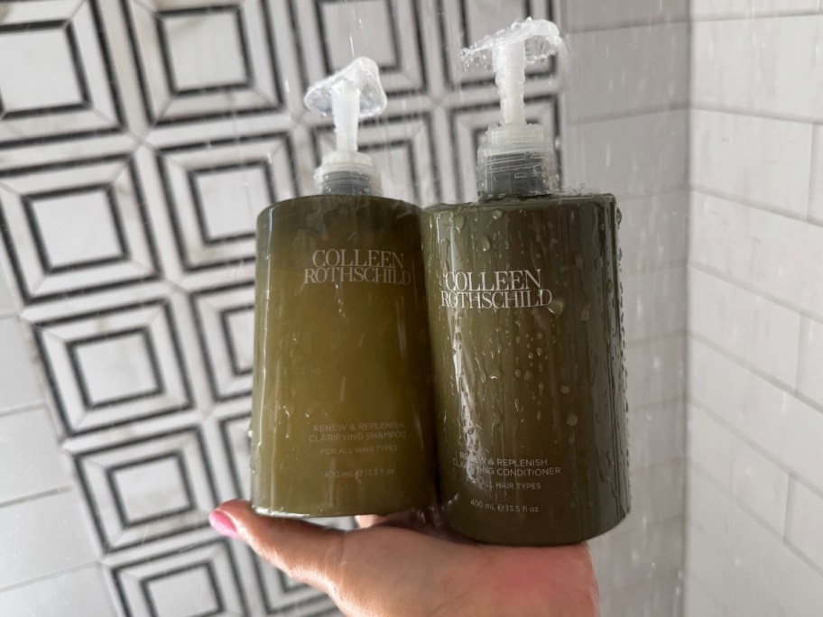 womans hand holding bottles of shampoo and conditioner 