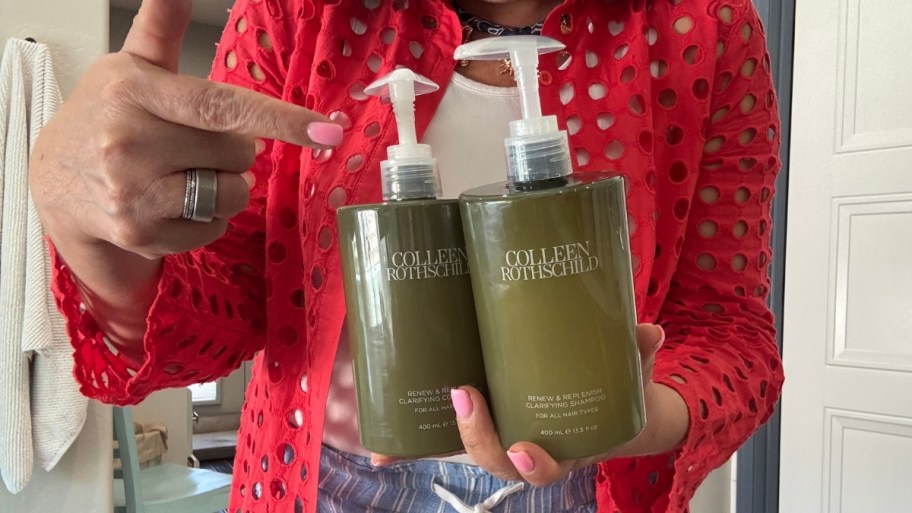 womans hand holding bottles of shampoo and conditioner 