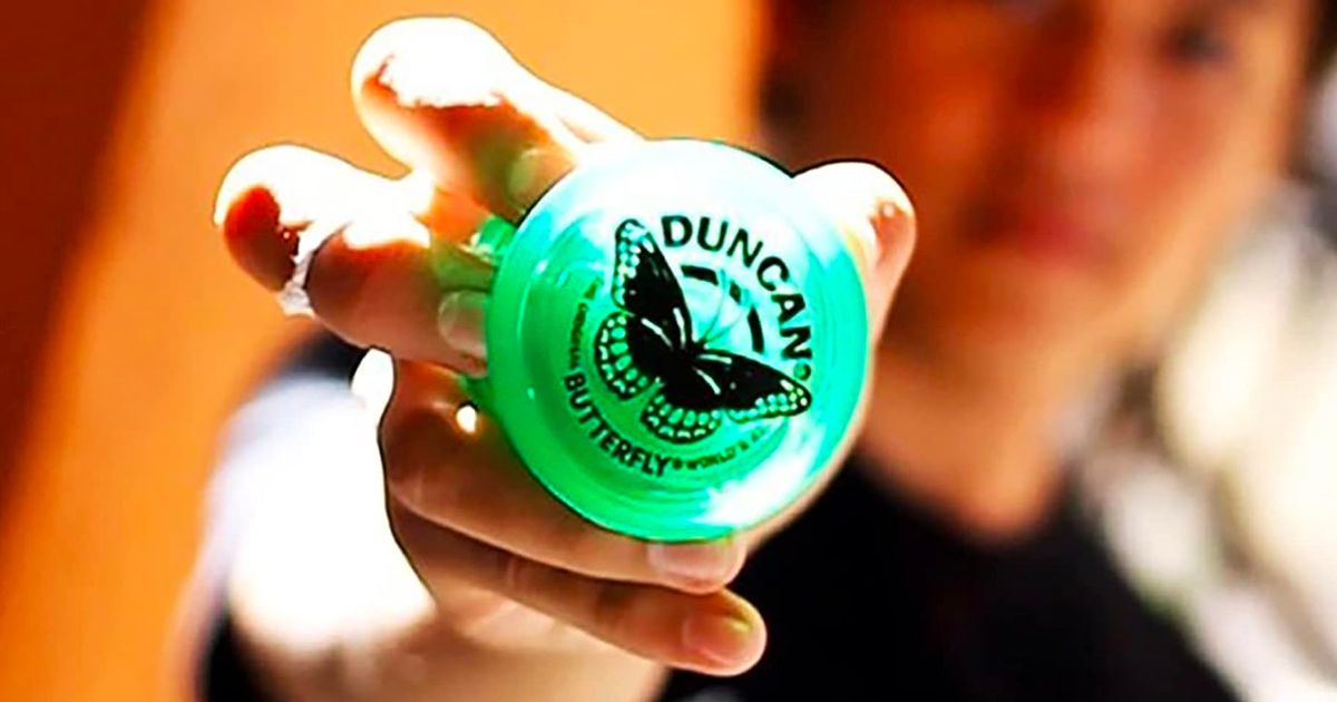 a girls hand holding a green duncan yo yo
