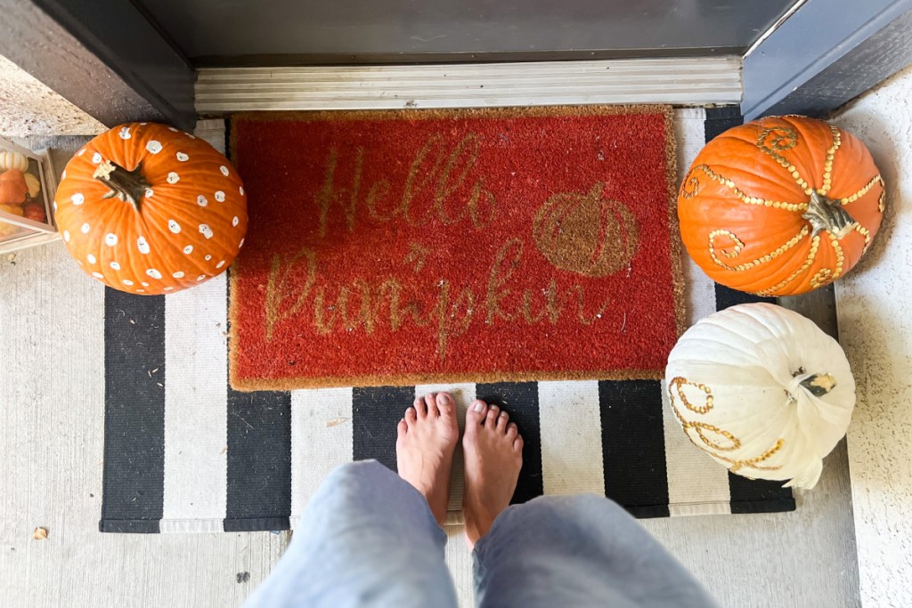 feet standing on porch entrway with pumpkins
