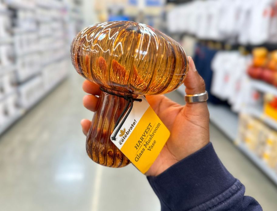 a woman's hand holding a glass mushroom vase