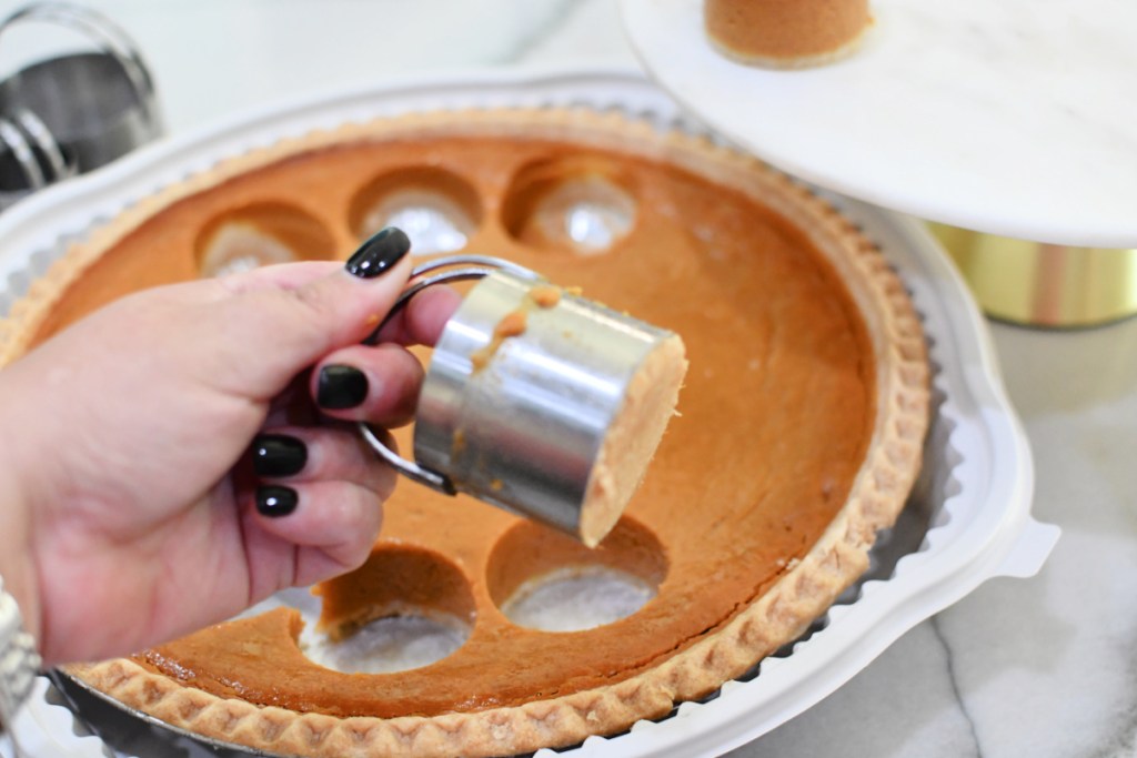 holdling a slice of pumpkin pie in a biscuit cutter