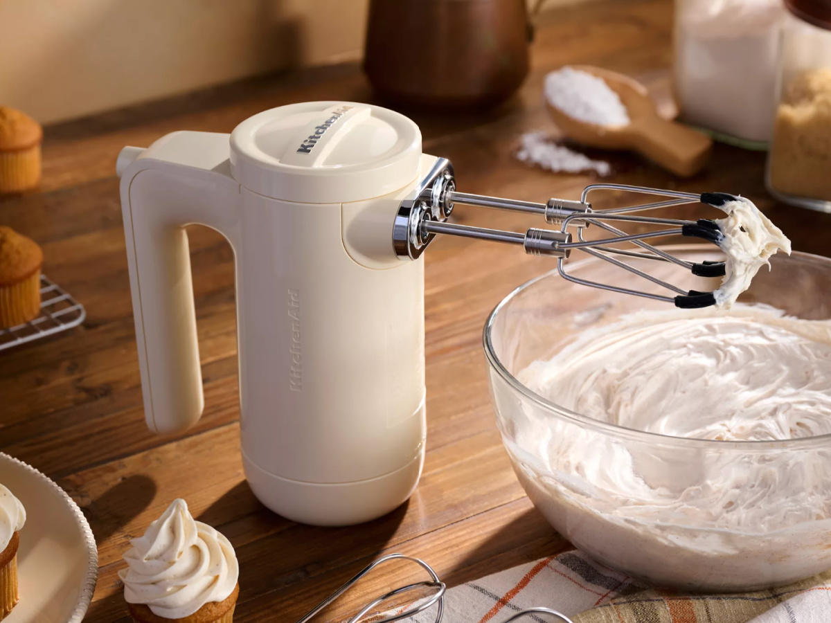 white cordless hand mixer over bowl of frosting