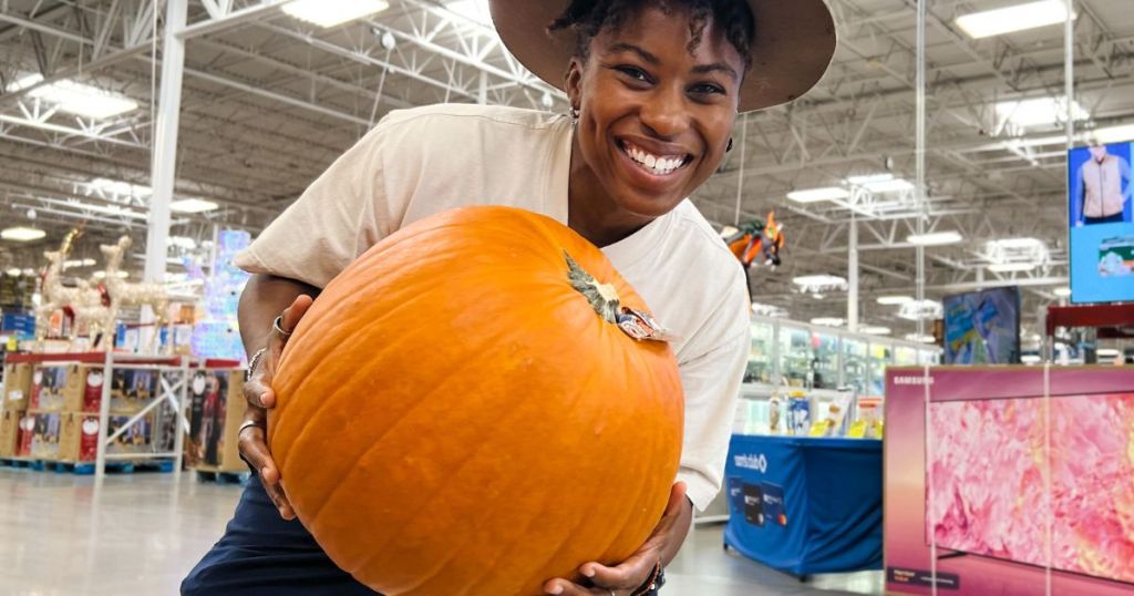 lady holding a big orange pumpkin