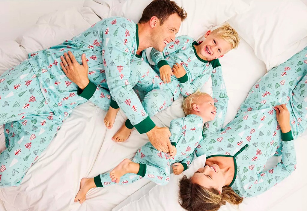 family wearing matching blue holiday pajamas in bed
