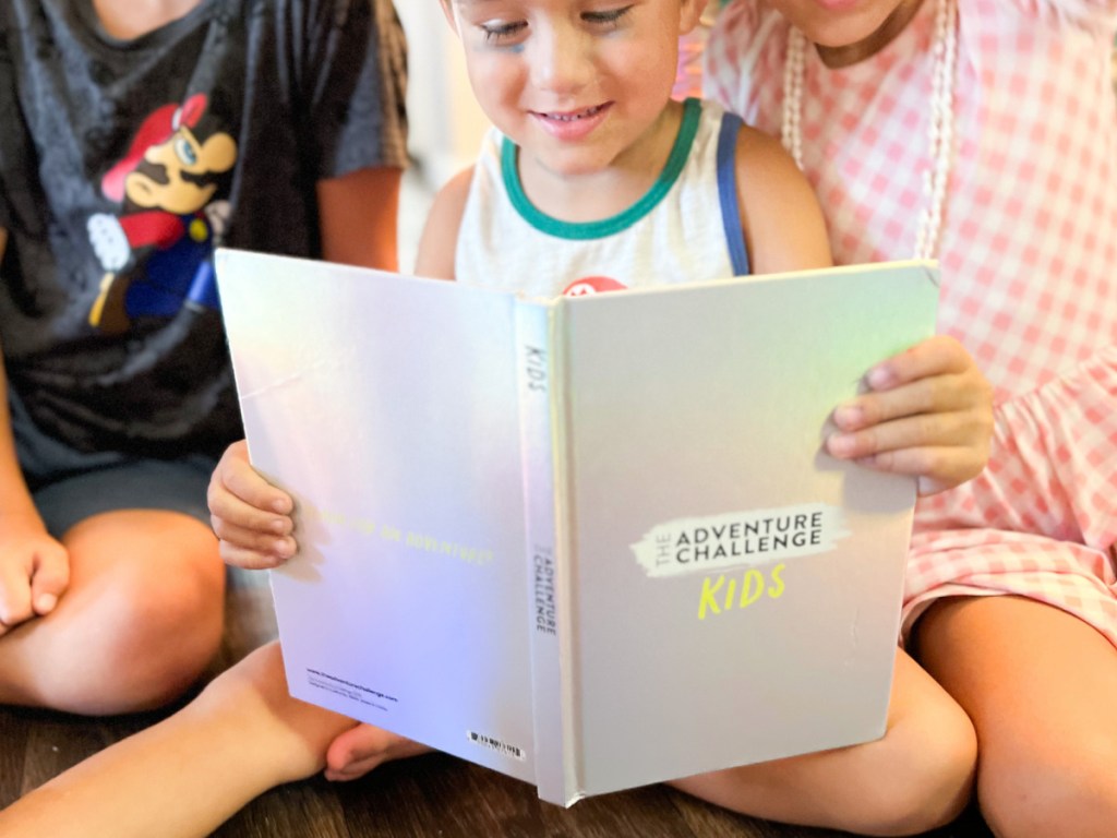 أطفال صغار يقرؤون كتاب تحدي المغامرة على الأرض