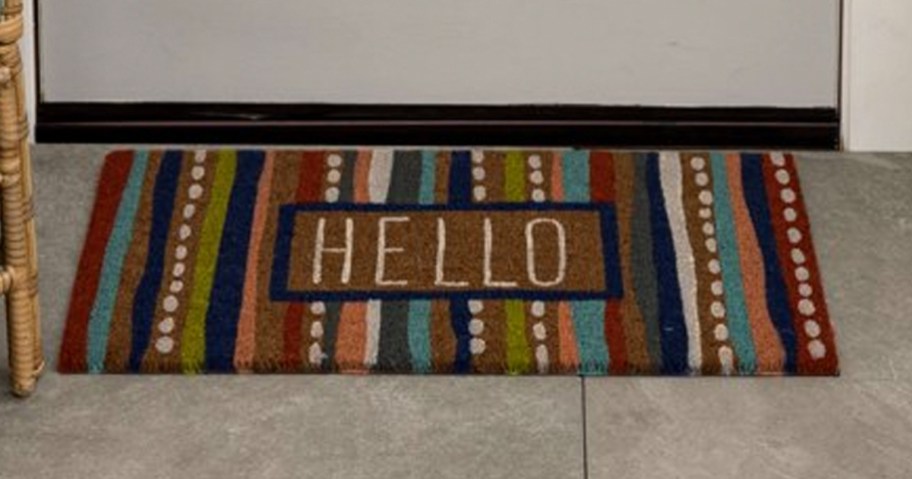 multicolor hello coir doormat sitting in front of door next to chair