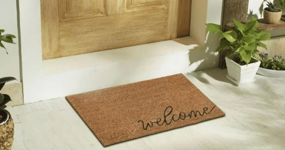 coir welcome doormat sitting in front of brown door