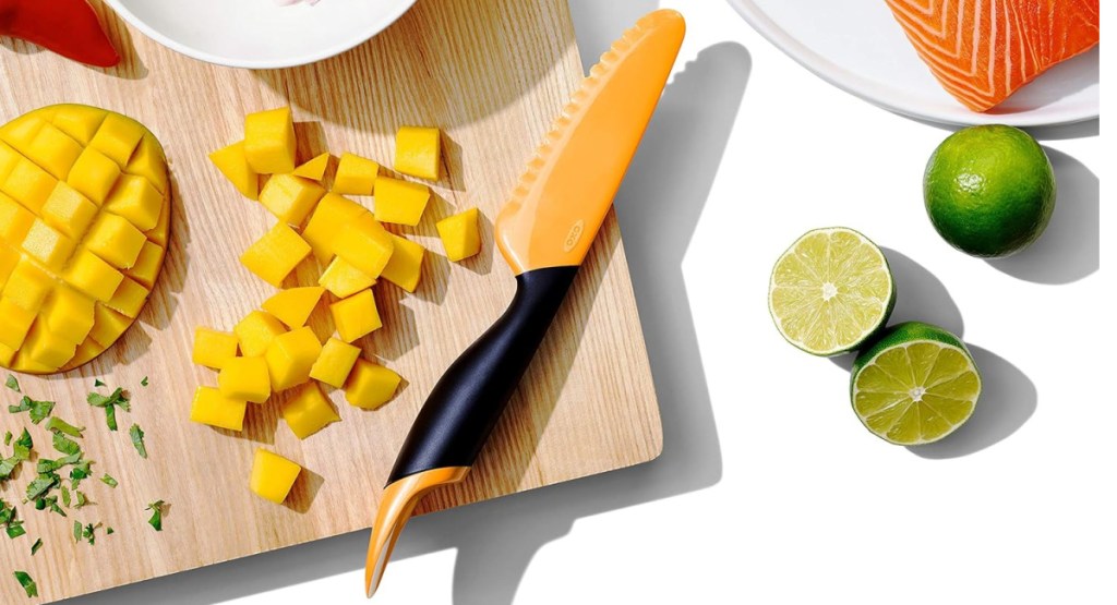 mango slicer and scooper displayed on cutting board with mango and lemons