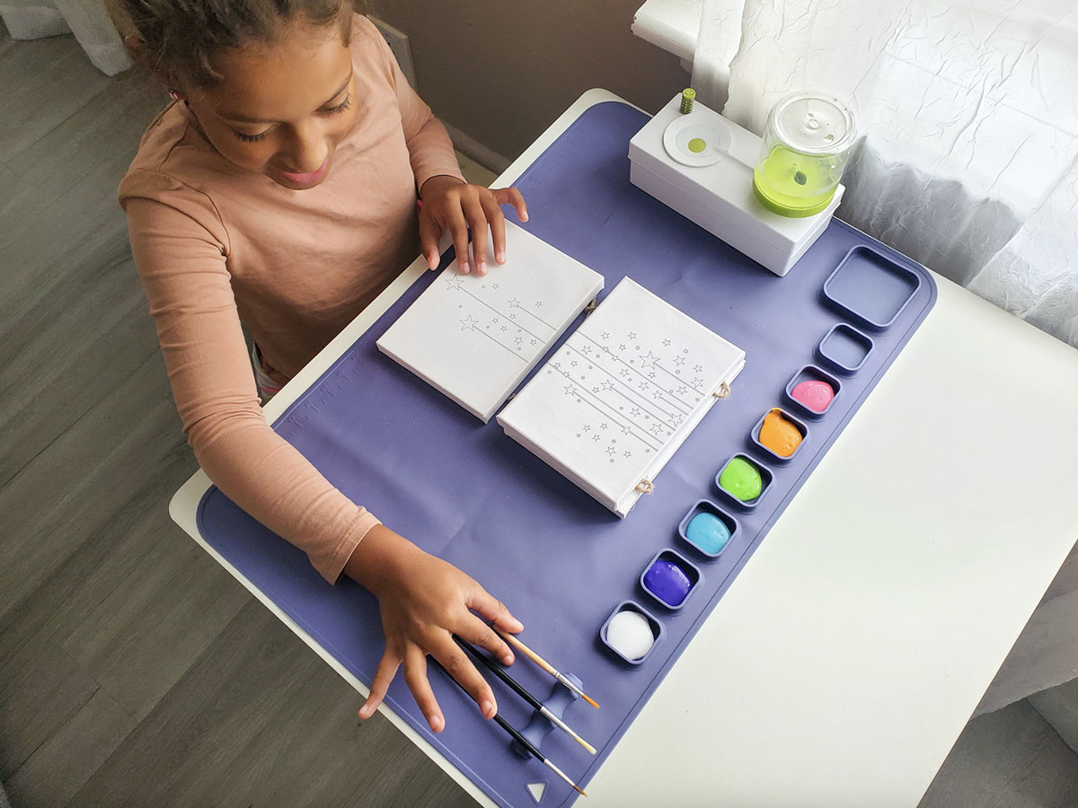 girl painting using purple painting mat