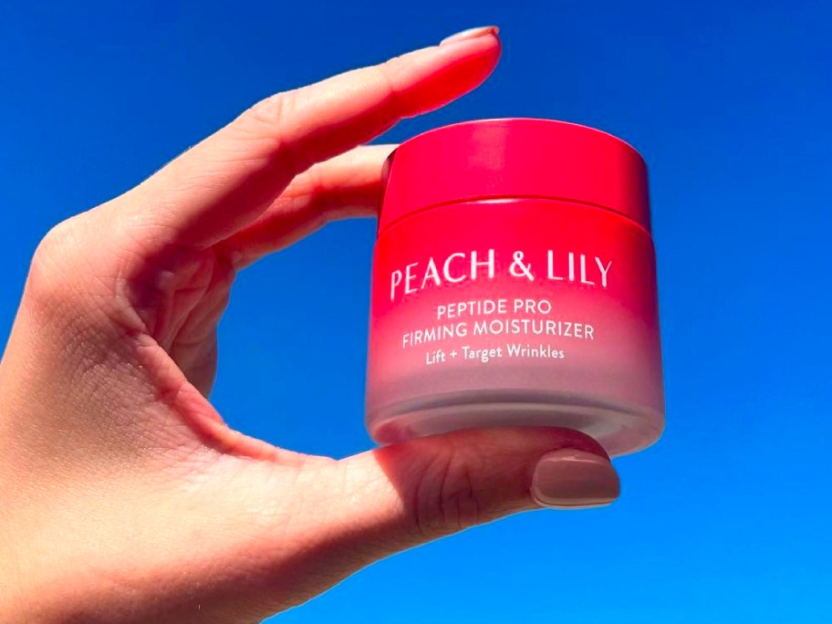 hand holding peach and lily moisturizer