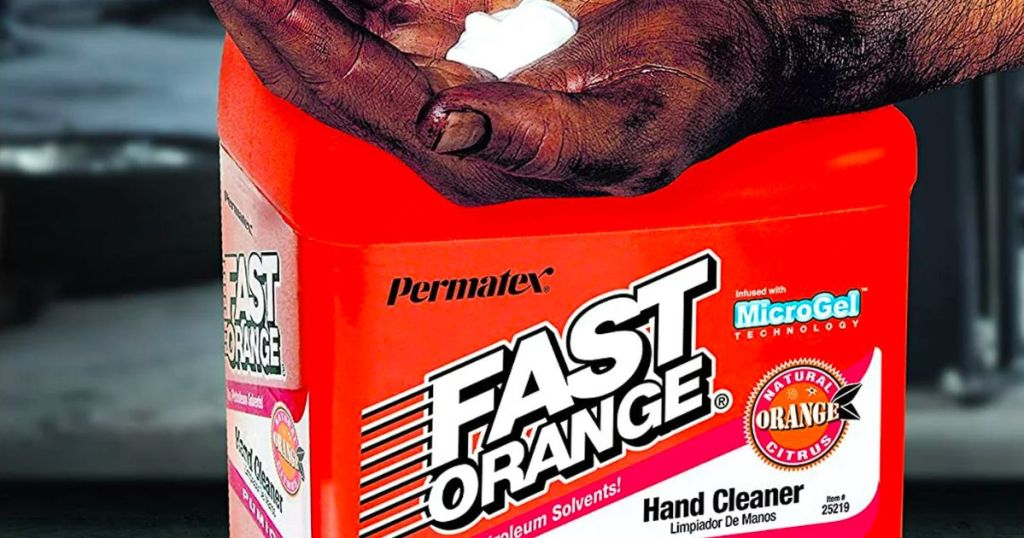  greasy hand with permatex dispensed in to palm in front of a jug of permatex fast orange