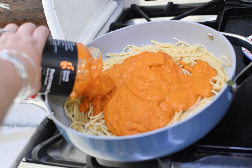 pouring good and gather pasta sauce onto cooked spaghetti