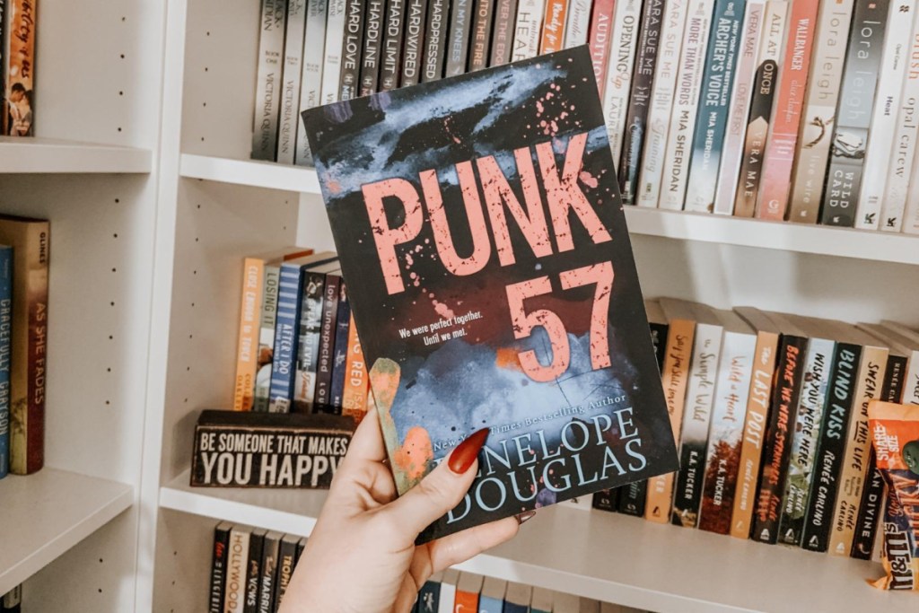 hand holding punk 57 book in front of bookcase