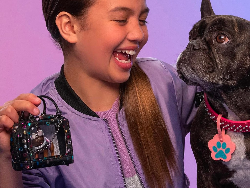 girl holding real littles dog toy next to her dog