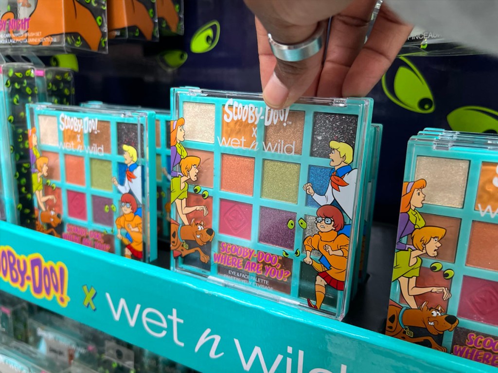 hand reaching for Wet N Wild Scooby Doo eyeshadow palette on display