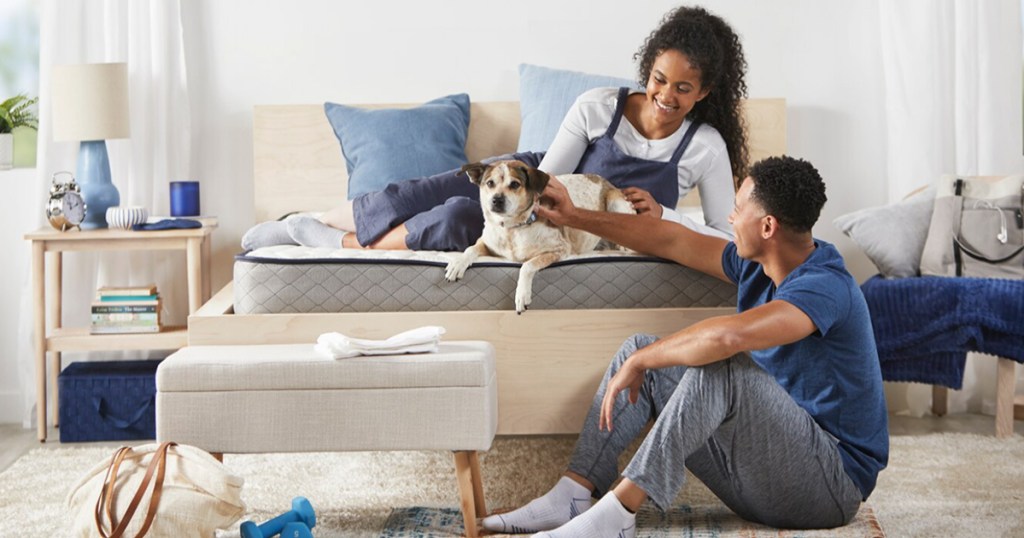 man and woman with dog on sleepy mattress in bedroom