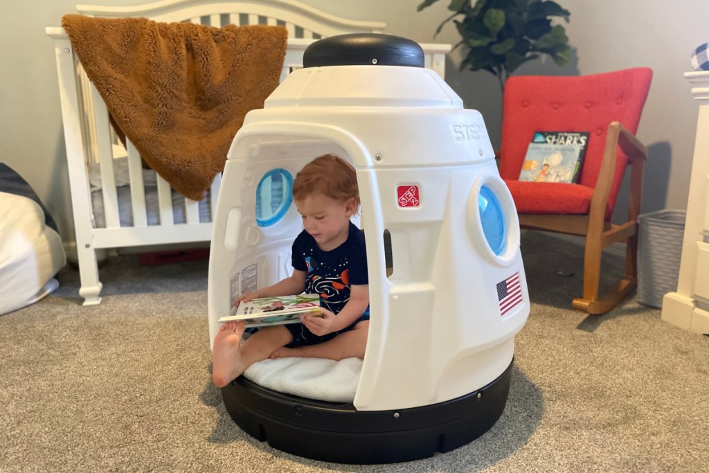 boy reading in rocket ship playhouse