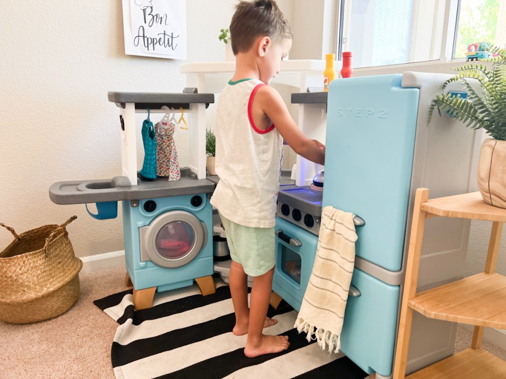 boy standing at play kitchen