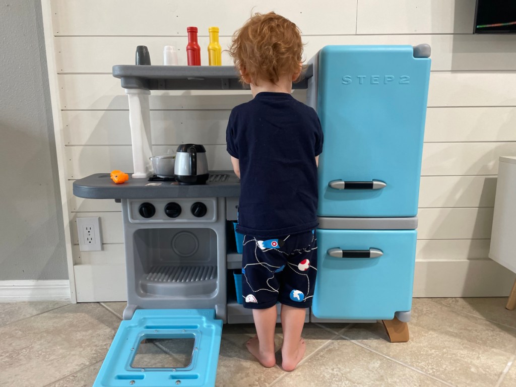 toddler standing at play kitchen