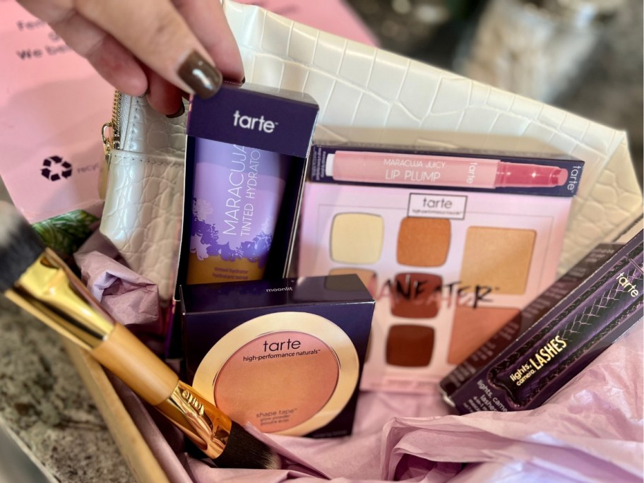 box with Tarte cosmetics makeup items and tan color makeup bag
