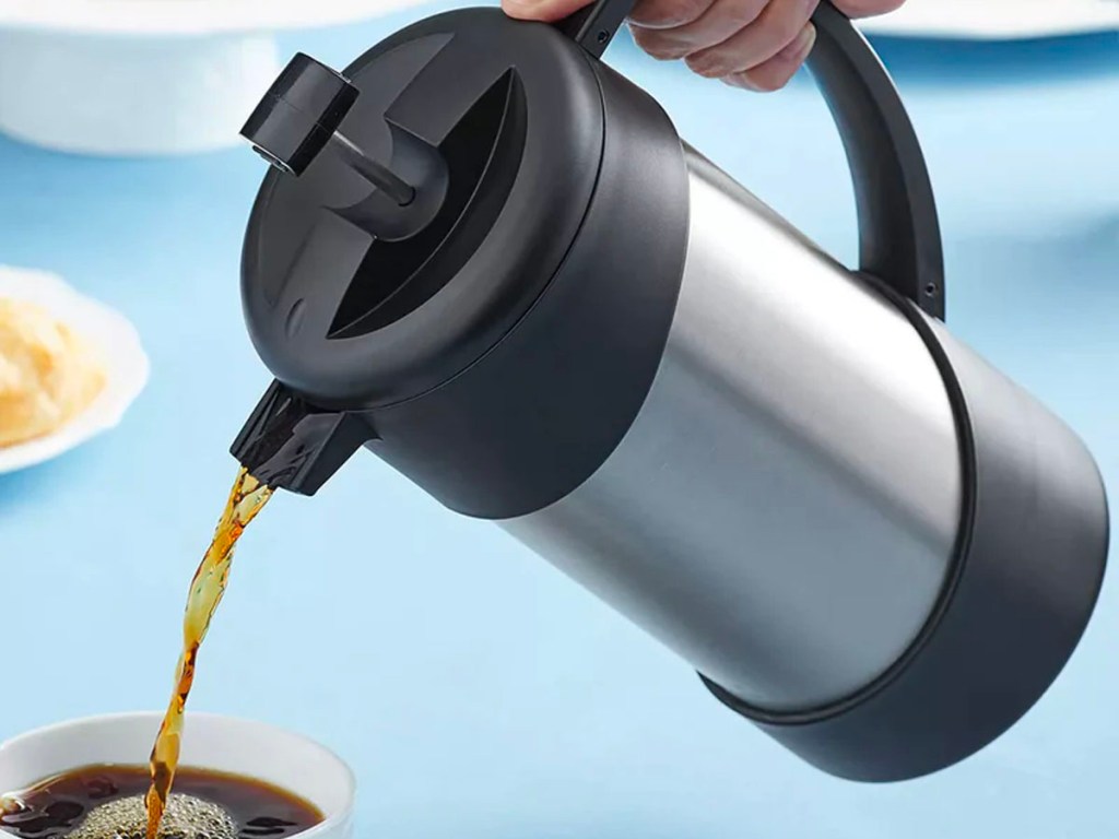hand pouring thermos press into coffee cup