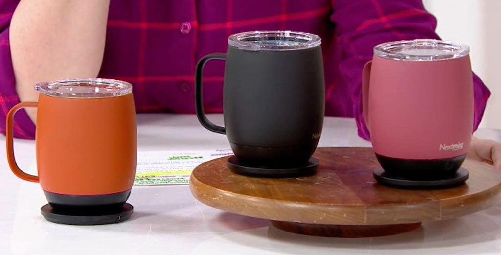 three next mugs displayed on the table in orange black or pink