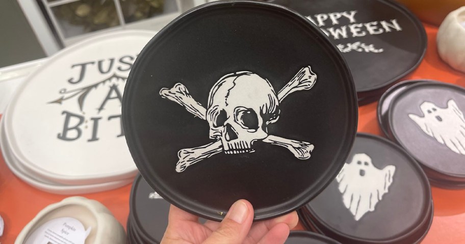 hand holding black stoneware plate with skull 