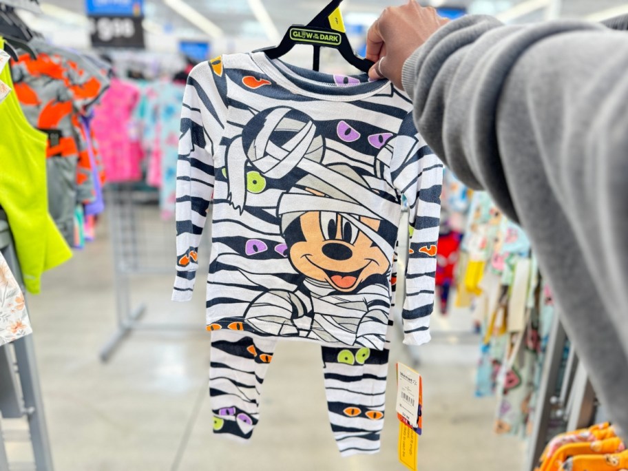 hand holding a set of toddler's pajamas with Mickey Mouse as a mummy on them