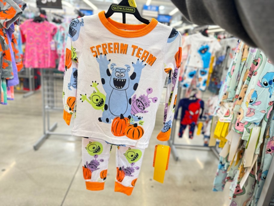 hand holding a set of kid's Halloween Pajamas with Monster's Inc characters on them