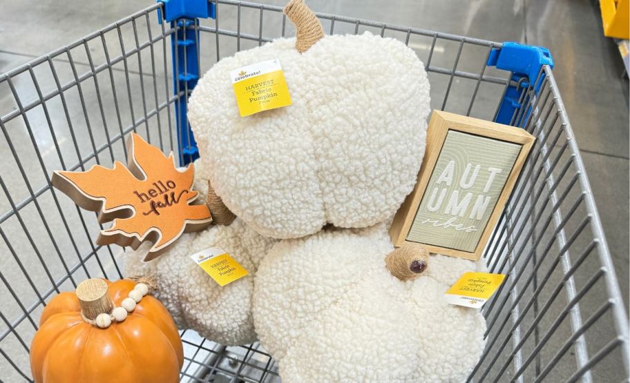 white walmart sherpa pumpkins with wooden wall decor in a walmart cart