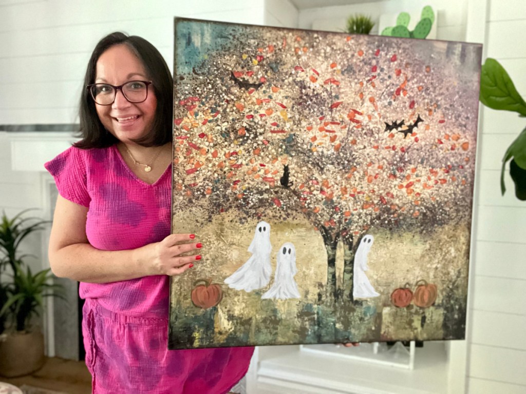 woman holding thrift store painting with ghosts