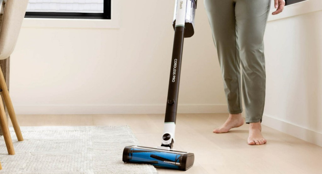 woman using the Shark Cordless Pro Stick Vacuum Cleaner w_ Clean Sense IQ on a rug and floor