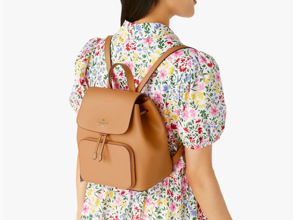 woman wearing a floral dress and a beige backpack