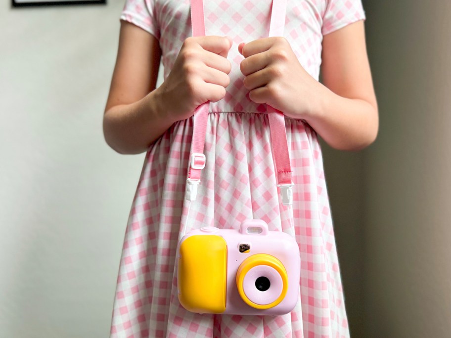 girl holding pink camera and lanyard