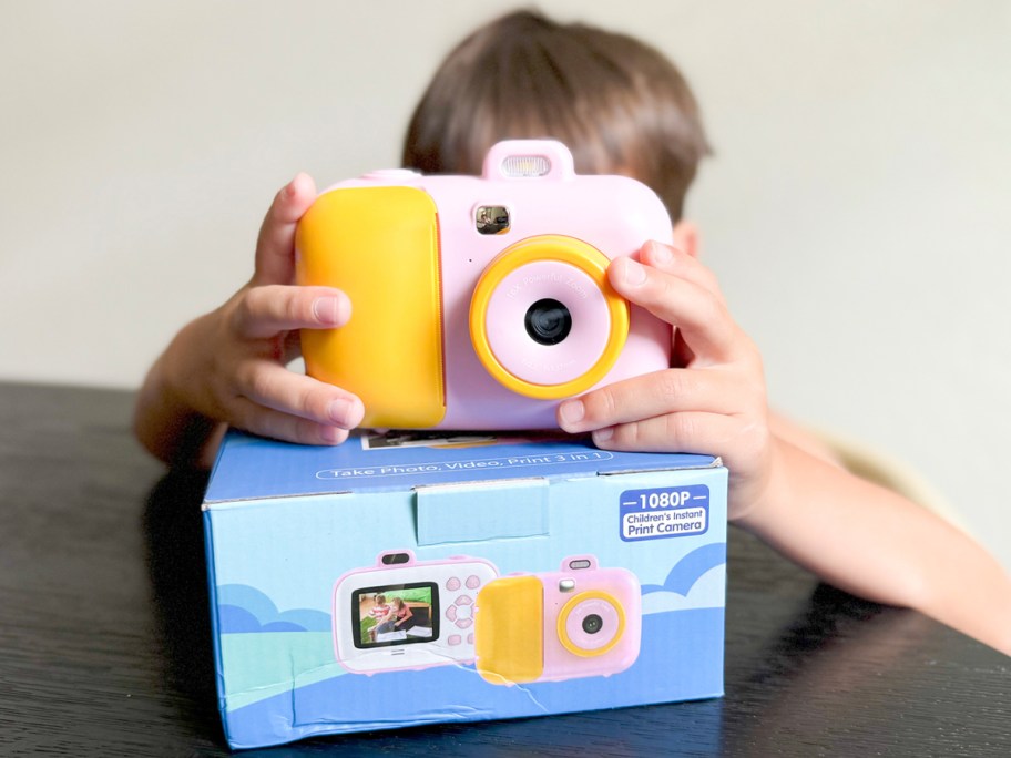 boy holding pink camera with blue box