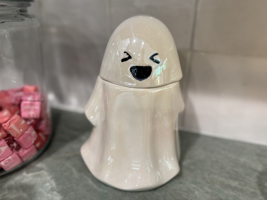 white ghost candy jar on a kitchen counter next to a jar of starbursts