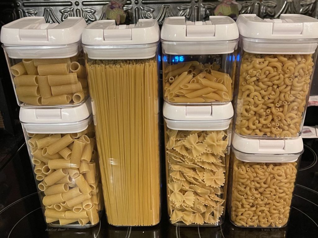7 food storage container sets stacked, filled with different types of pasta