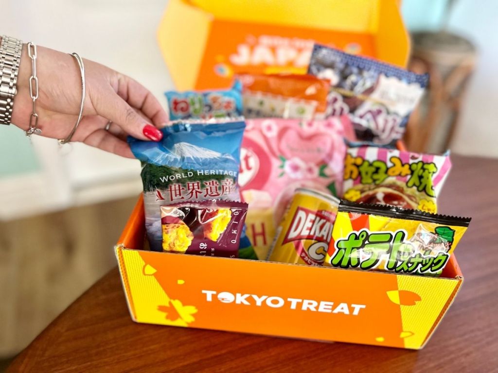 Tokyo Treat Surprise Box open with treats and hand reaching to one