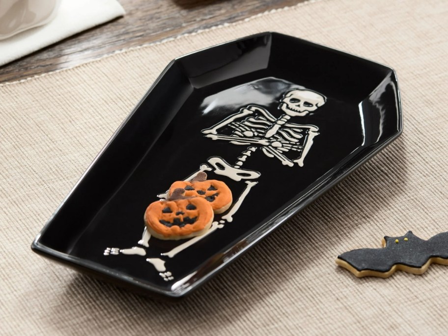 black coffin shaped serving tray with a skeleton on it