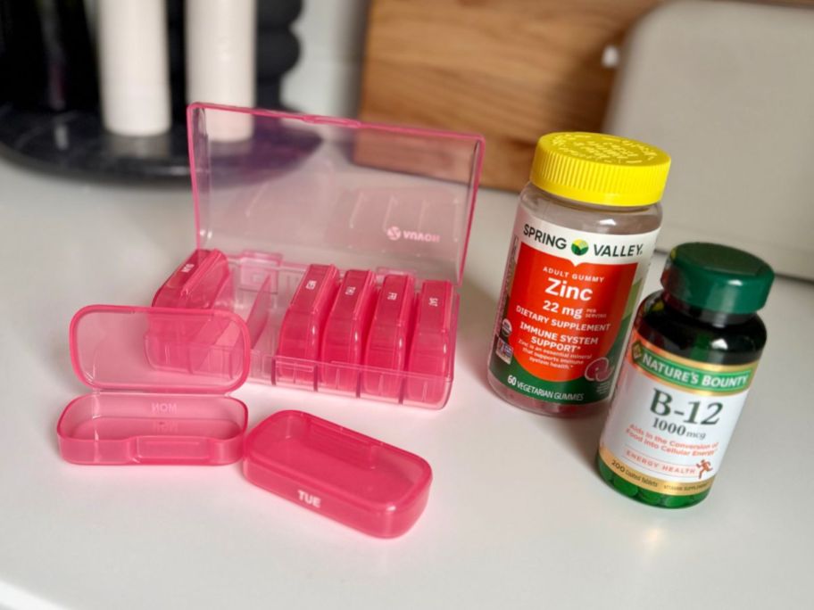 AUVON Pill Organizer next to vitamin bottles on counter