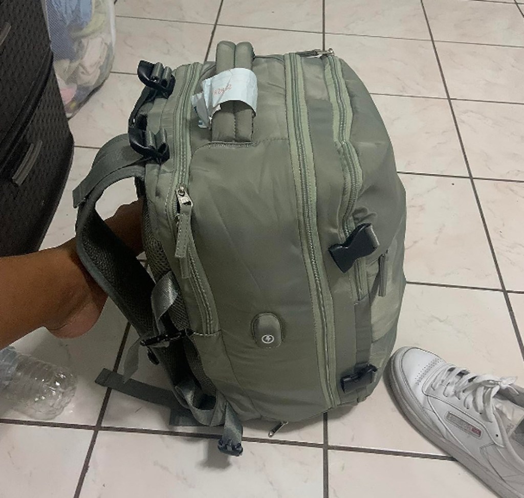 Green travel, backpack on tile floor with dirty white shoe